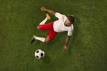 Image showing Top view of caucasian football or soccer player on green background of grass