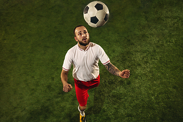 Image showing Top view of caucasian football or soccer player on green background of grass