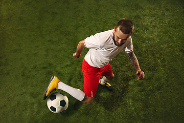 Image showing Top view of caucasian football or soccer player on green background of grass