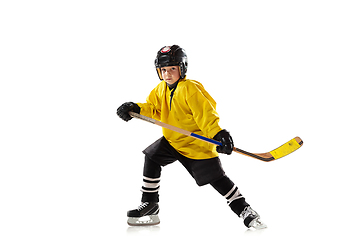 Image showing Little hockey player with the stick on ice court and white studio background