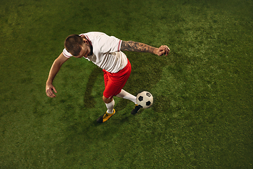 Image showing Top view of caucasian football or soccer player on green background of grass