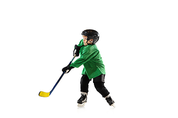 Image showing Little hockey player with the stick on ice court and white studio background