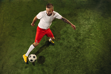 Image showing Top view of caucasian football or soccer player on green background of grass