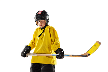 Image showing Little hockey player with the stick on ice court and white studio background