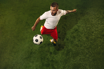 Image showing Top view of caucasian football or soccer player on green background of grass