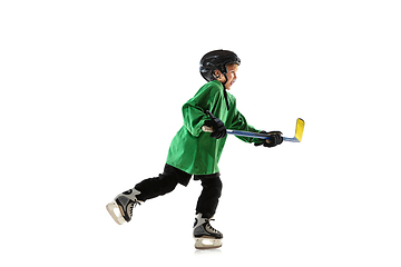 Image showing Little hockey player with the stick on ice court and white studio background