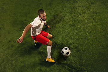 Image showing Top view of caucasian football or soccer player on green background of grass