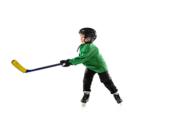 Image showing Little hockey player with the stick on ice court and white studio background