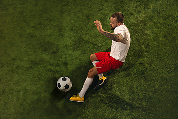 Image showing Top view of caucasian football or soccer player on green background of grass