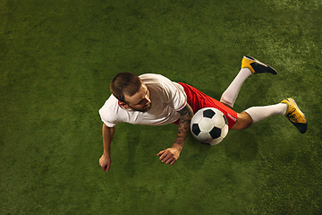 Image showing Top view of caucasian football or soccer player on green background of grass