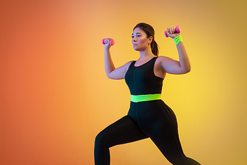 Image showing Young caucasian plus size female model\'s training on gradient orange background