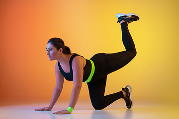 Image showing Young caucasian plus size female model\'s training on gradient orange background