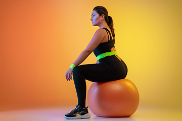 Image showing Young caucasian plus size female model\'s training on gradient orange background