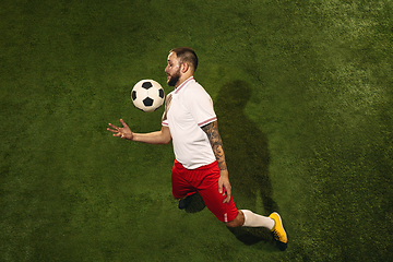 Image showing Top view of caucasian football or soccer player on green background of grass