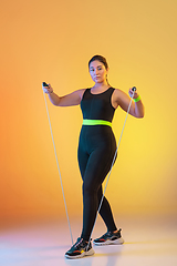 Image showing Young caucasian plus size female model\'s training on gradient orange background