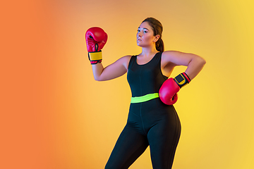 Image showing Young caucasian plus size female model\'s training on gradient orange background