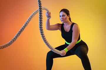 Image showing Young caucasian plus size female model\'s training on gradient orange background