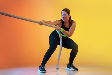 Image showing Young caucasian plus size female model\'s training on gradient orange background