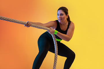 Image showing Young caucasian plus size female model\'s training on gradient orange background