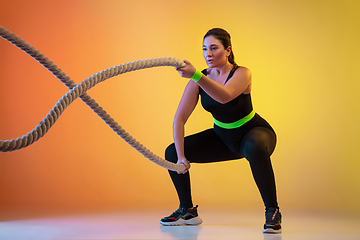 Image showing Young caucasian plus size female model\'s training on gradient orange background