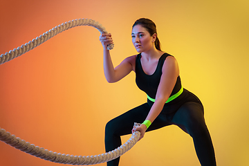 Image showing Young caucasian plus size female model\'s training on gradient orange background