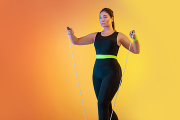 Image showing Young caucasian plus size female model\'s training on gradient orange background