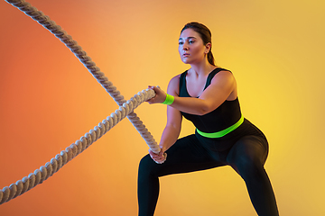 Image showing Young caucasian plus size female model\'s training on gradient orange background