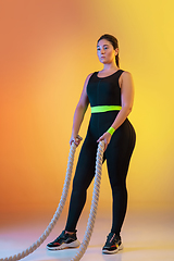 Image showing Young caucasian plus size female model\'s training on gradient orange background