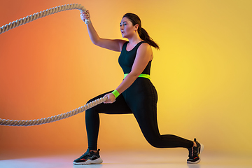 Image showing Young caucasian plus size female model\'s training on gradient orange background