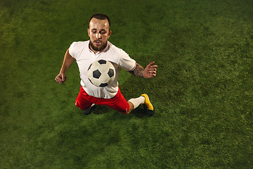 Image showing Top view of caucasian football or soccer player on green background of grass