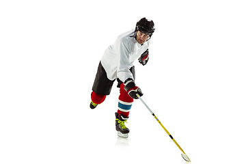 Image showing Young male hockey player with the stick on ice court and white background