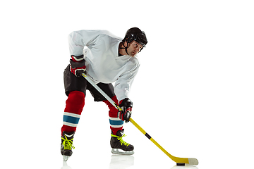 Image showing Young male hockey player with the stick on ice court and white background