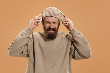 Image showing Portrait of Caucasian man in headphones and hat isolated on light background.