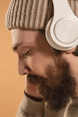Image showing Close-up Caucasian man in headphones and hat isolated on light background.