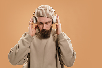 Image showing Portrait of Caucasian man in headphones and hat isolated on light background.