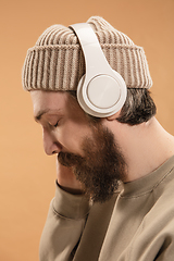 Image showing Portrait of Caucasian man in headphones and hat isolated on light background.