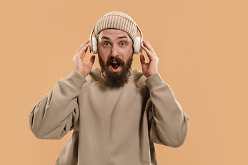 Image showing Portrait of Caucasian man in headphones and hat isolated on light background.