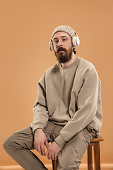 Image showing Portrait of Caucasian man in headphones and hat isolated on light background.