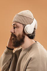 Image showing Portrait of Caucasian man in headphones and hat isolated on light background.