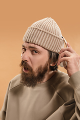 Image showing Portrait of Caucasian man in headphones and hat isolated on light background.