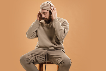 Image showing Portrait of Caucasian man in headphones and hat isolated on light background.