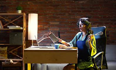 Image showing Young Caucasian woman during online cooking lesson through laptop.