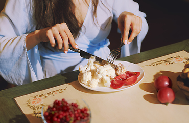 Image showing Vegetarian woman sitting at the table and eating healthy food