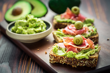 Image showing Guacamole dip or spread with open sandwiches and ham on wooden kitchen table