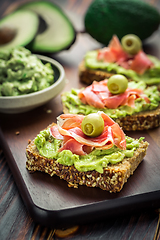 Image showing Guacamole dip or spread with open sandwiches and ham on wooden kitchen table