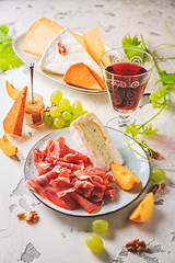 Image showing Ham and cheese platter with grapes and red wine
