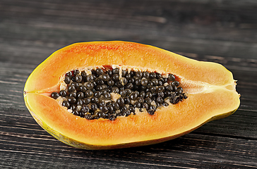 Image showing Half papaya on a wooden table. Papaya lies on dark boards