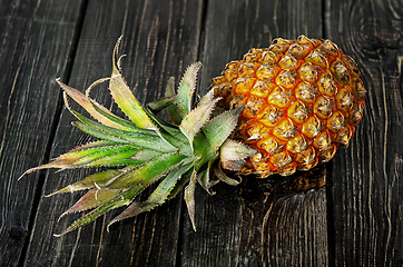 Image showing Ripe pineapple lies on a wooden table