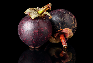 Image showing Two ripe mangosteen one after another on a black