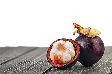 Image showing Whole and opened mangosteen on table isolated on white